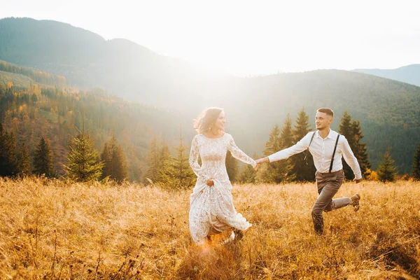 A boho wedding in the mountains. Happy newlyweds running at sunset