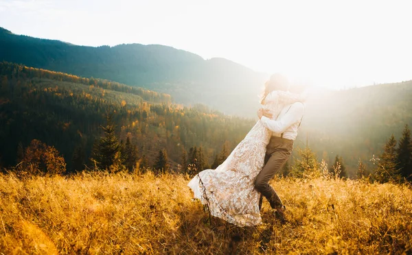 Beautiful newlyweds walking in the mountains. Wedding in boho style.