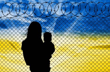 Ukraynalı mülteciler - çocuklu bir anne, Ukrayna bayrağı şeklinde gökyüzüne dikenli tellerin yanında. Ukraynalı mülteci kavramı. Rusya ile Ukrayna 'da Savaş ve Kriz
