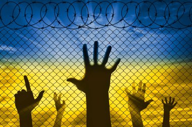 Ukraynalı mültecilerin kaldırılmış ellerinin silueti Ukrayna bayrağı şeklinde gökyüzüne karşı dikenli tellerin yanındaki sınırda. Rusya ile Ukrayna 'da kriz ve savaş kavramı
