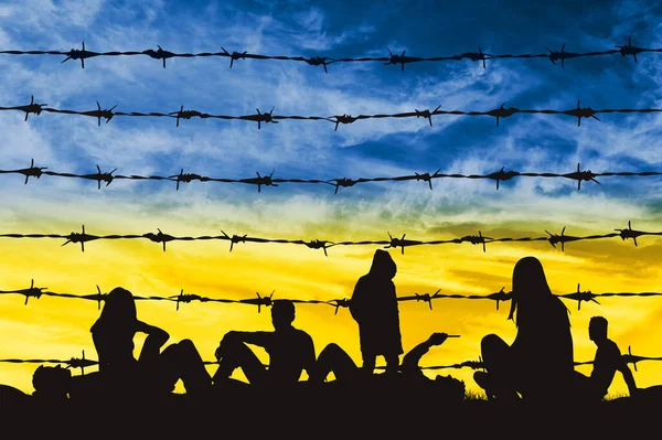 Ukraynalı mülteciler bir mülteci kampında, dikenli tellerin yanında gökyüzüne karşı Ukrayna bayrağı şeklinde. Ukraynalı mülteci kavramı. Rusya ile Ukrayna 'da Savaş ve Kriz