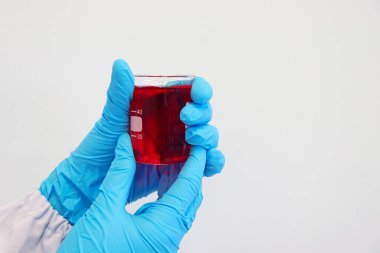 Bilim adamı, besin katkı maddesi Ponceau 4 R 'yi meyve suyu örneklerinde gıda renklendirme analizi ve kimya laboratuvarında deney yapmak için nitril eldivenlerle besin kabında kırmızı çözeltileri tutuyor..