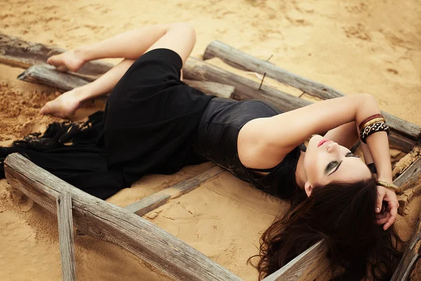 Moda dziewczyny leżące na piasku pustyni. — Zdjęcie stockowe