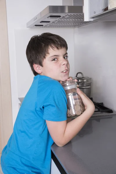 Kleiner Junge nimmt Süßigkeiten aus einem hohen Küchenschrank — Stockfoto