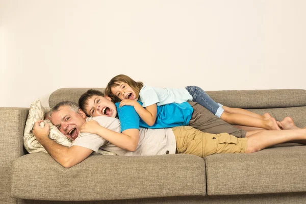 Отец и дети играют на диване — стоковое фото