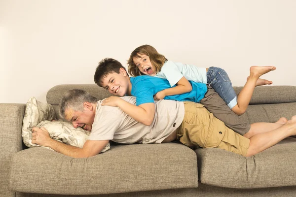 Отец и дети играют на диване — стоковое фото