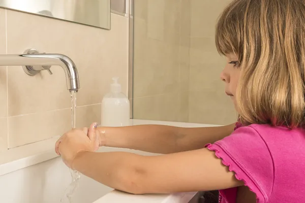 Çocuk ellerini yıkıyor.
