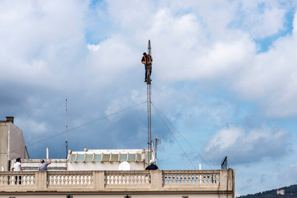 Barcelona, Spain - October 1, 2021: Construction worker disassembling an antenna on the roof of a residential building in Barcelona, Spain