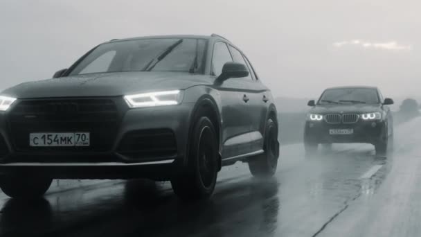 АЛТАЙ, РОССИЯ - 29 ИЮНЯ 2021: Audi Q5 и BMW X4 едут по шоссе во время сильного дождя — стоковое видео