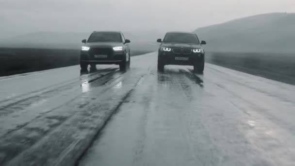 ALTAI, RUSSIA - 29 JUNE 2021: BMW speeds up on the highway and outruns Audi in the rain — Stock Video