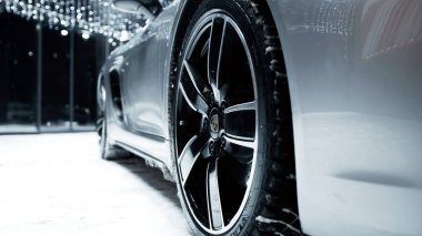 PETERSBURG, RUSSIA - 12 ARALIK 2020: Gümüş Porsche 718 Boxter geceleri açık havada duruyor, kar yağıyor. tekerlekler yakın plan