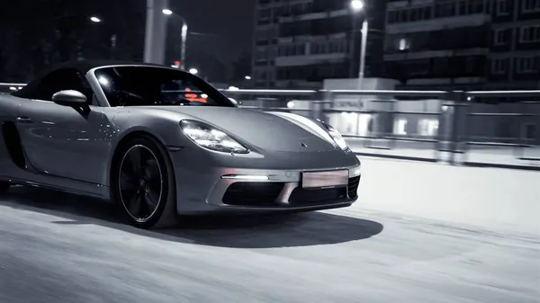 ST. PETERSBURG, Oroszország - 12 DECEMBER 2020: Ezüst Porsche 718 Boxter végiglovagol egy gyönyörű város utcáin. Fényes fényszórók — Stock Fotó