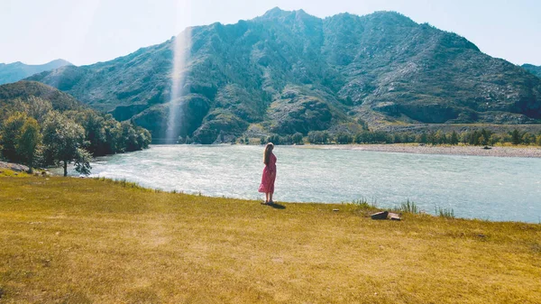女性の長い赤いドレスの背景に山と2つの川の端を見下ろす。ドローン映像 — ストック写真