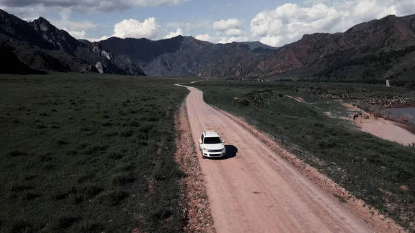 白い車は山の中の狭い道路を通って駆動します。ドローン映像 — ストック写真