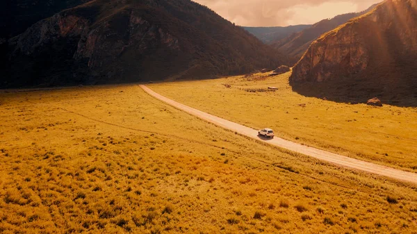 白い車は山の中の狭い道路を通って駆動します。ドローン映像 — ストック写真