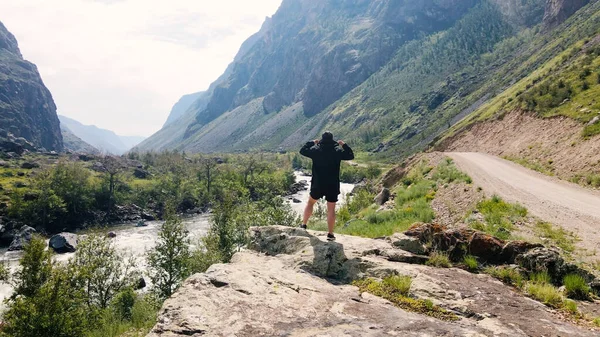 Um homem fica à beira de um penhasco com um anoraque preto. Katu-Yaryk desfiladeiro Chulyshman Valley. Altai... — Fotografia de Stock