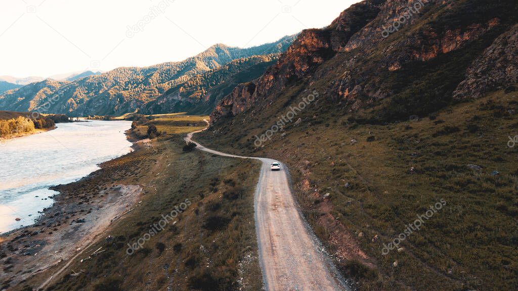 White car drives through narrow road in the mountains. Drone footage
