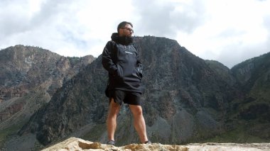 Uçurumun kenarında siyah bir anorak giyen bir adam. Katu-Yaryk Kanyonu Chulyshman Vadisi. Altai.