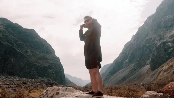 Um homem fica à beira de um penhasco com um anoraque preto. Katu-Yaryk desfiladeiro Chulyshman Valley. Altai... — Fotografia de Stock