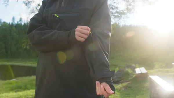 Девушка в очках открывает карман серого анорака на фоне пейзажа — стоковое фото