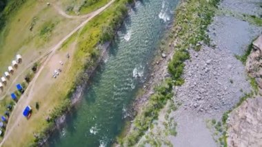 FPV insansız hava aracı Altai 'de kayaların arasında kayalık bir nehre dalıyor.