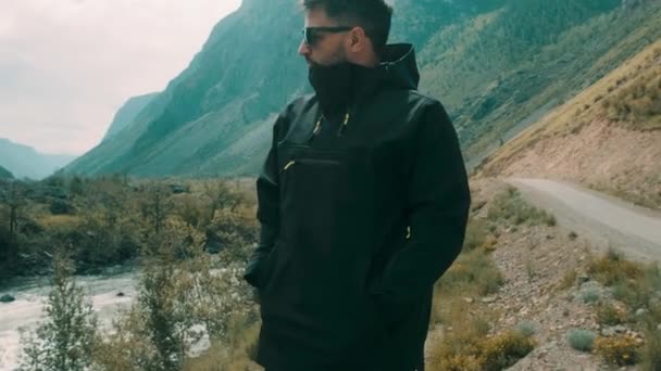 Un homme reste au bord d'une falaise portant un anorak noir. Katu-Yaryk canyon Chulyshman Valley. Altaï — Video