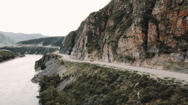 暗い灰色の車は山の中の狭い道路を通って駆動します。ドローン映像 — ストック写真