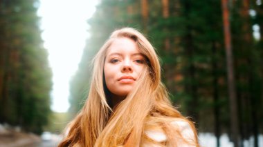 Muhteşem altın saçlı güzel bir kadın. Eğlenceli genç kız saçlarını dalgalandırmak için başını sallıyor. Çekici genç bayan dönüp kameraya bakıyor.