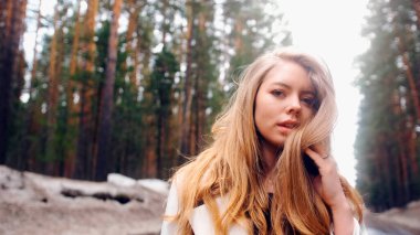 Muhteşem altın saçlı güzel bir kadın. Eğlenceli genç kız saçlarını dalgalandırmak için başını sallıyor. Çekici genç bayan dönüp kameraya bakıyor.