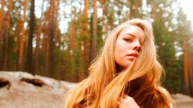 Muhteşem altın saçlı güzel bir kadın. Eğlenceli genç kız saçlarını dalgalandırmak için başını sallıyor. Çekici genç bayan dönüp kameraya bakıyor.