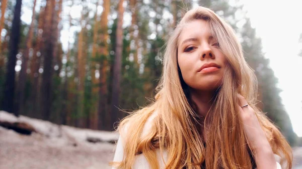Muhteşem altın saçlı güzel bir kadın. Eğlenceli genç kız saçlarını dalgalandırmak için başını sallıyor. Çekici genç bayan dönüp kameraya bakıyor.