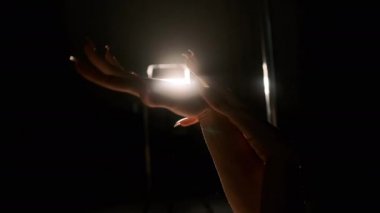 Kızlar ellerini arkadaki sert ışığın arka planına koyuyorlar. Yakın plan, siyah arkaplan