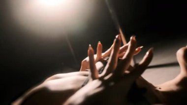 Seksi bir kız arka planda elleriyle boynuna sarılıyor. Siyah arka plan. Ellerini yaklaştır.