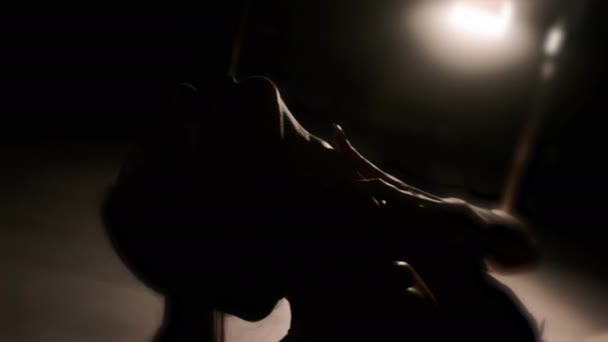 Uma menina sexy abraça seu pescoço em uma luz de fundo com as mãos. Fundo preto. Close-up das mãos — Vídeo de Stock