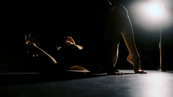 Sert ışıklandırma yapan seksi bir kadın bacaklarını ve kemerlerini sırtına kaldırıyor. Siyah arkaplan. — Stok fotoğraf
