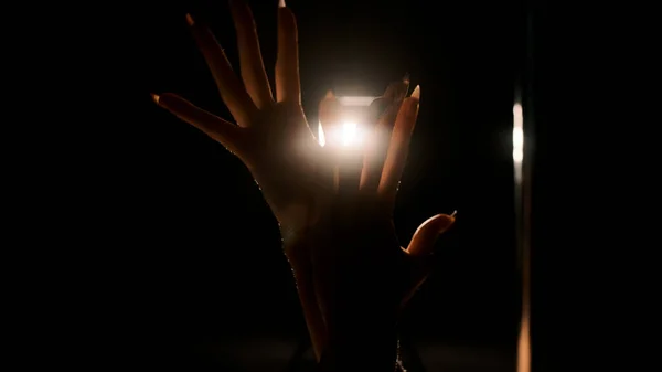 Die Hände der Mädchen vor dem Hintergrund des harten Rücklichts. Nahaufnahme, schwarzer Hintergrund — Stockfoto