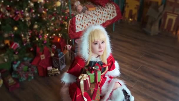 Leuk meisje cosplaying kerst Miku Santa jurk met geschenken. Nieuwjaarself. Zit op de vloer. — Stockvideo