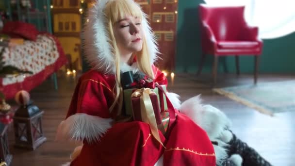 Aranyos lány cosplaying Christmas Miku Mikulás ruha ajándékokkal. Újévi manó. A földön ül. — Stock videók