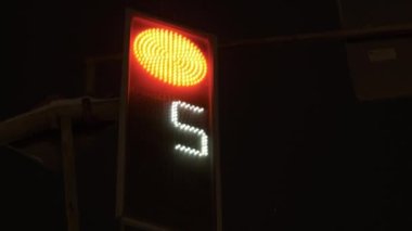 Trafik ışığı kırmızısı geri sayıyor. Yeşil ışık yanıyor. Gece kıştır. Kar yağıyor.