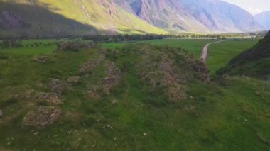 Yeşil anorak giymiş bir adam tepeye doğru koşuyor. Altai Chelyshman Vadisi