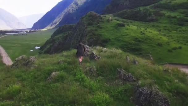 Мужчина бежит вверх по холму в зелёном анораке. Алтайская Челышманская долина — стоковое видео