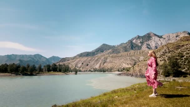 Lady in abito rosso lungo si affaccia sul bordo di due fiumi con montagne sullo sfondo. Filmati dei droni — Video Stock