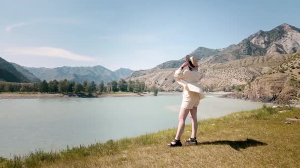 Egy bézs ruhás lány a dombon, aki a csodálatos hegyi kilátásra néz. Drónfelvételek — Stock videók