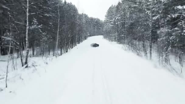 MOSCOW, RUSSIA - 13 DECEMBER 2020: Black luxury sports car is drifting in a snowy forest in winter. Drone view — ストック動画