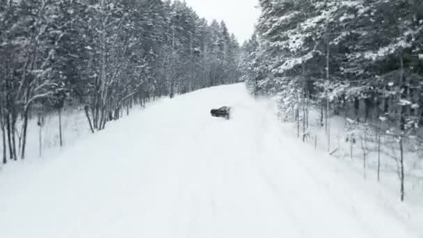 MOSCOW, RUSSIA - 13 DECEMBER 2020: Black luxury sports car is drifting in a snowy forest in winter. Drone view — стоковое видео