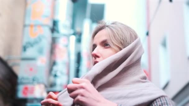 A girl of Slavic appearance wraps a scarf around her neck in the Japanese quarter — Stock video