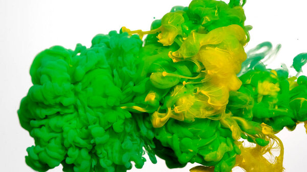 Colored acrylic paints in water. Green and yellow watercolor ink in water on a white background. Green cloud of ink on a white background. Abstract background. Drops of green and yellow ink in water.