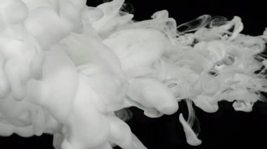 Suyun içinde yavaş hareket eden sıvı süt boyaları. Kozmik büyü soyut arka plan. Ekran koruyucu, rahatlatıcı meditasyon arka planı. Siyah arkaplanda beyaz mürekkep bulutu.