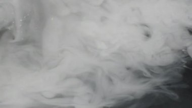 Evdeki beyaz kulüpler. Siyah arka planda beyaz mürekkep bulutu. Suyun içinde yavaş hareket eden sıvı süt boyaları. Ekran koruyucu, meditatif soyut arkaplan dinlendirici.