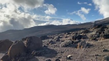 Dağ manzarası. İnanılmaz güzel mavi gökyüzü ve beyaz bulutlar. Yükseklerden Karanga kampının görüntüsü. Aralık 'ta Kilimanjaro' ya tırmanmak. Birkaç yürüyüşçü dağdan iner..